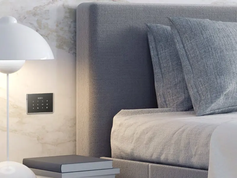 Black touch switch with a small display mounted beside a bed