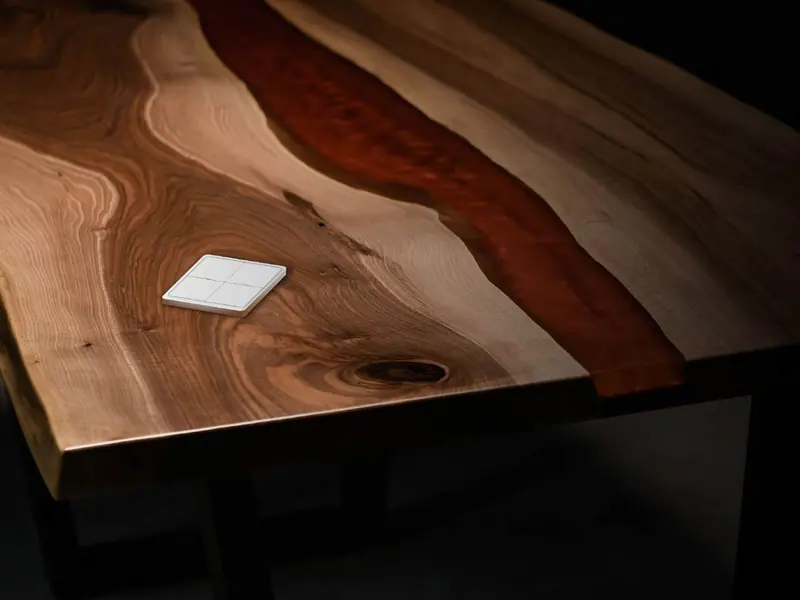 White wireless four-button switch resting on a wooden table